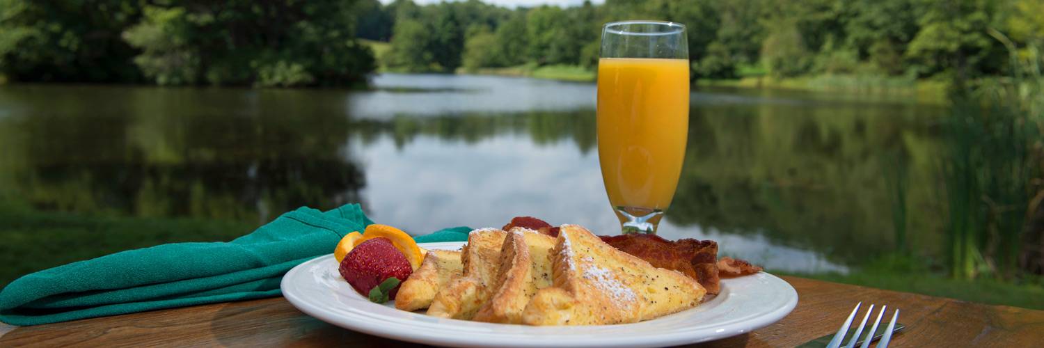 A breakfast plate with French Toast, Bacon, and Orange Juice at Peaks of Otter Lodge