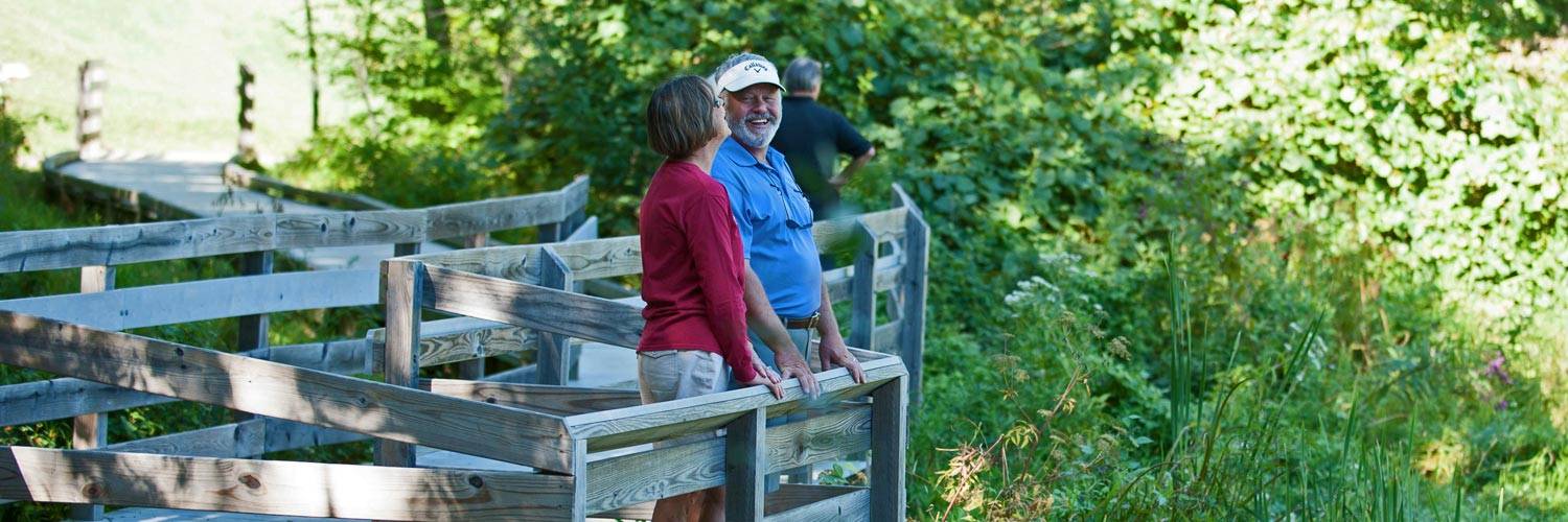 Two guests at Peaks of Otter Lodge take in the view of Abbott Lake
